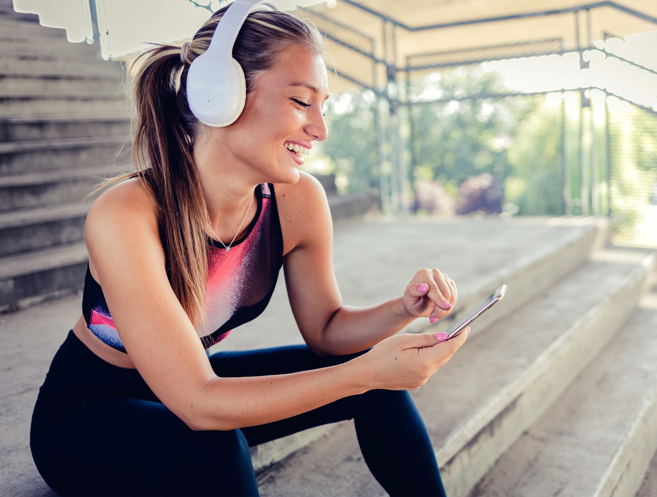 Junge, sportliche Frau mit Headphones sieht sich die freestream Website auf ihrem Handy an