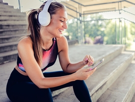 Junge, sportliche Frau mit Headphones sieht sich die freestream Website auf ihrem Handy an